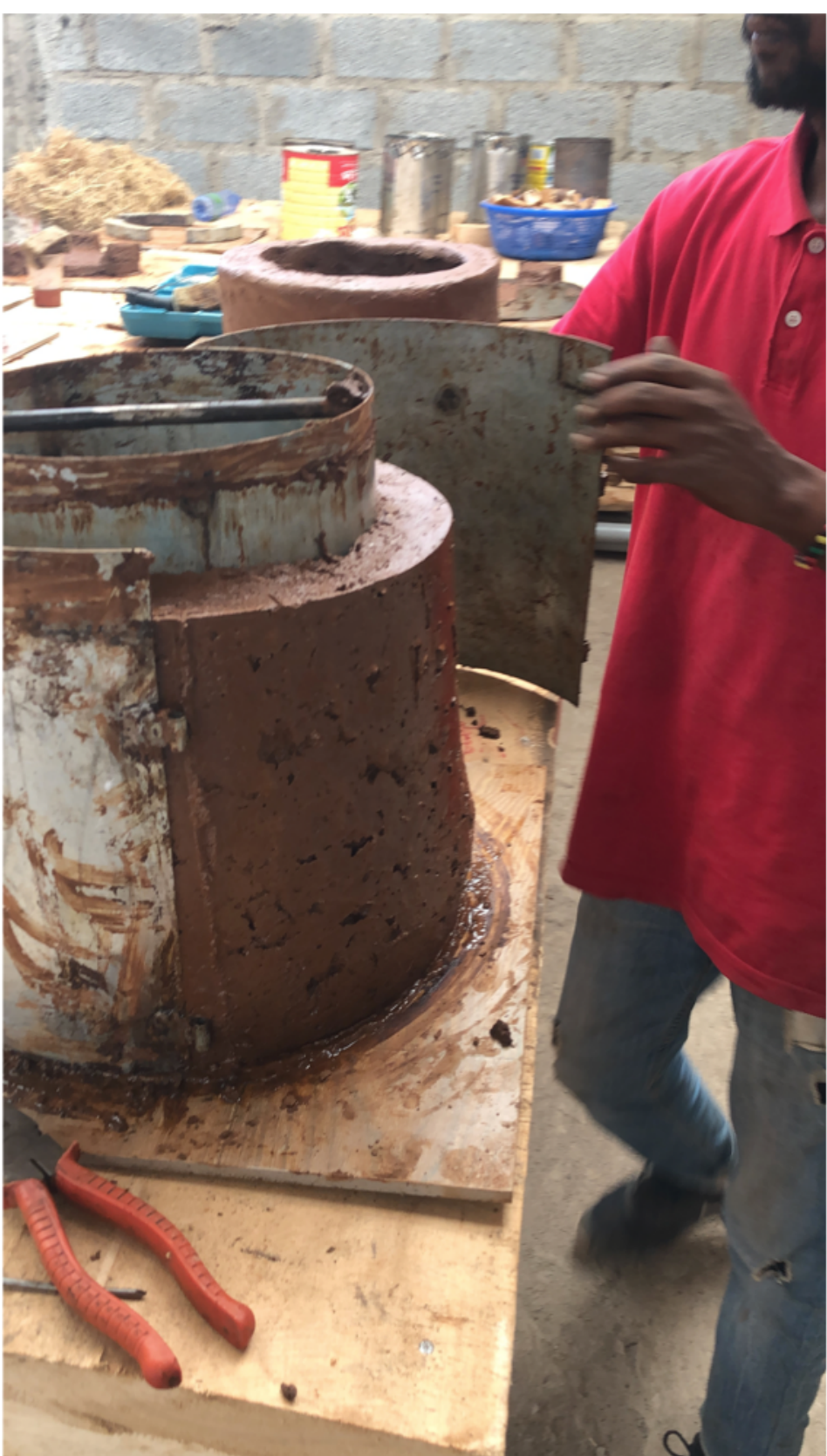 Producer holding a sheet-metal mold against a part-built clay stove