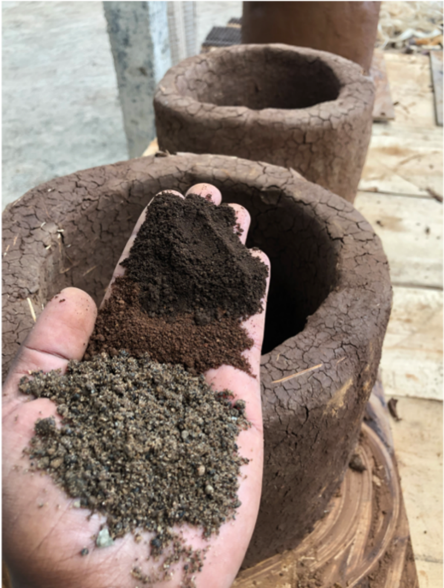 Layered soil and sand sample held over a finished clay stove body