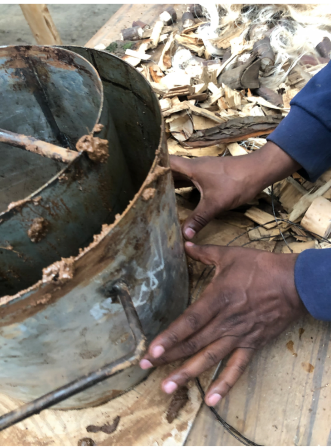 Hands shaping a metal can liner used inside the stove body