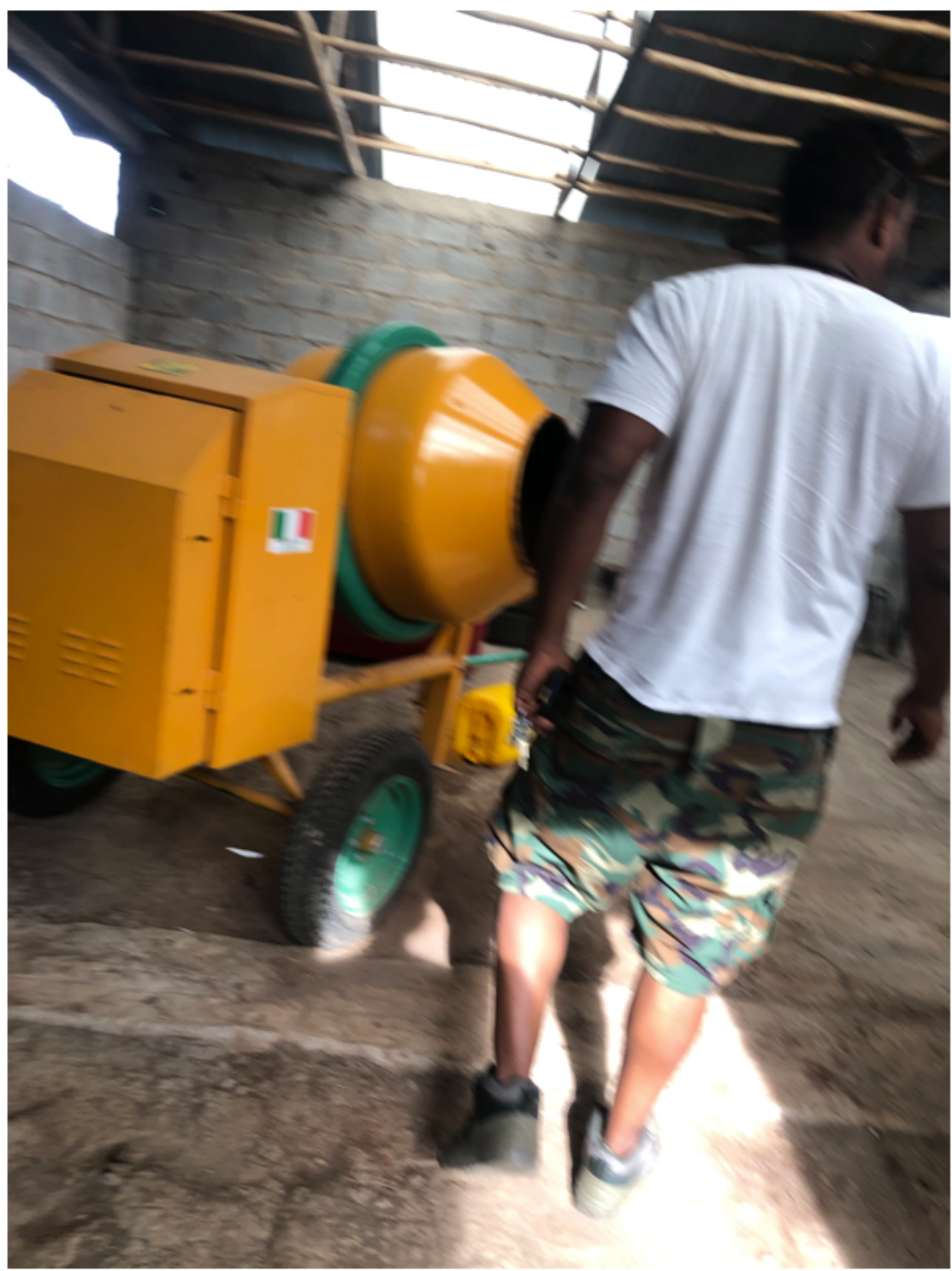 Worker pushing a small concrete mixer used to prepare the clay mixture